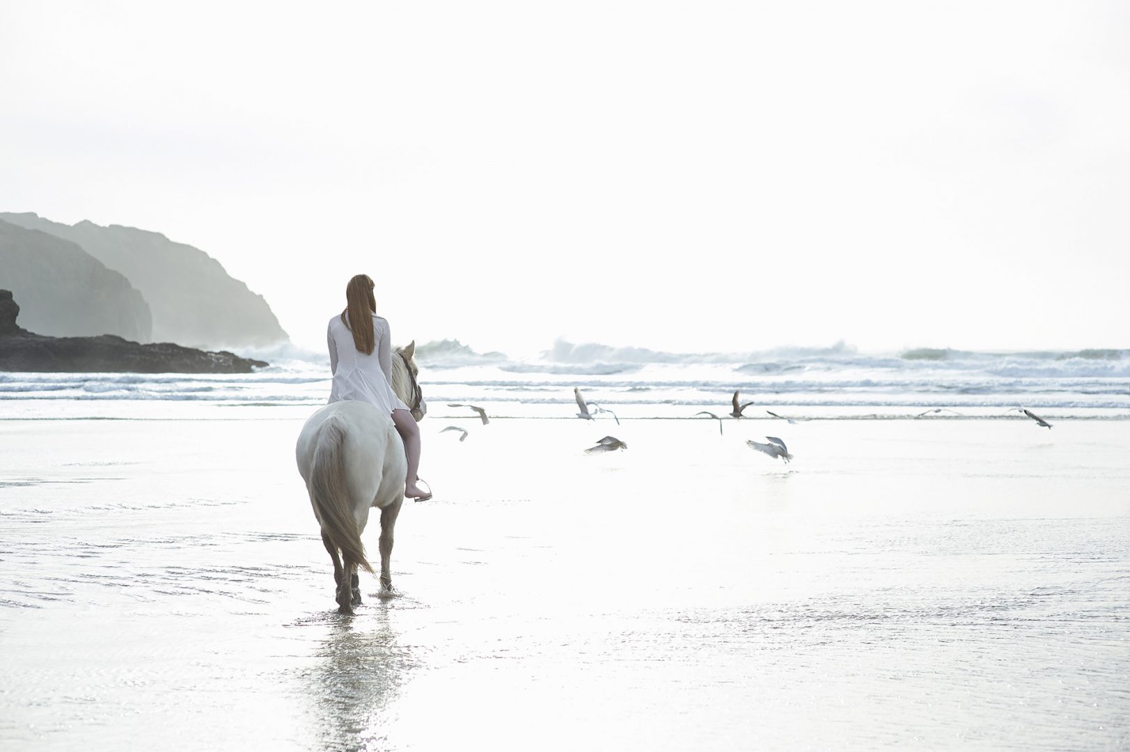 Photograph of a girl riding a horse on a Cornish beach